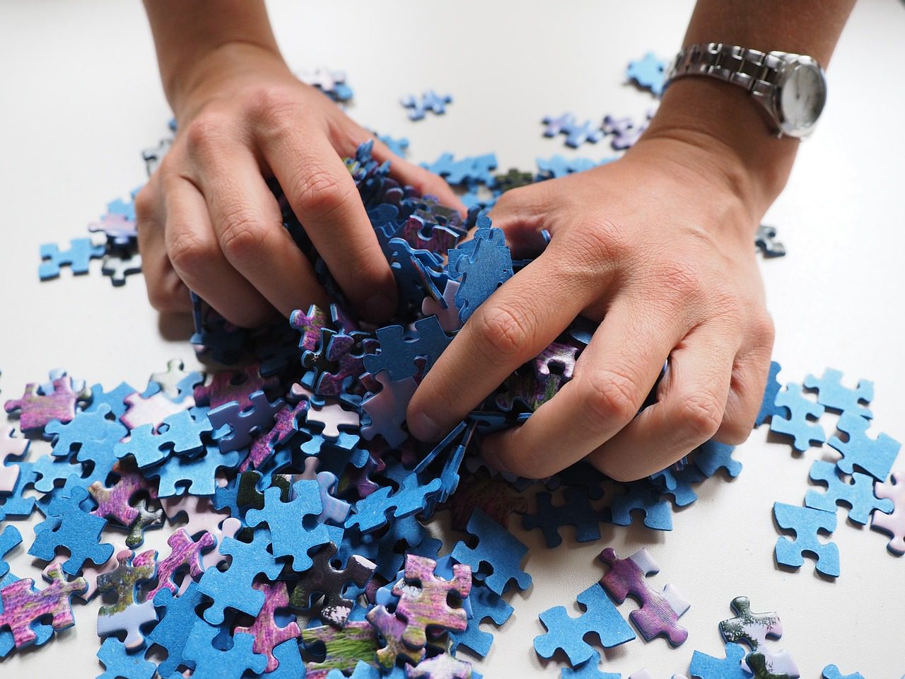 Two Hands Grabbing Several Jigsaw Puzzle Pieces